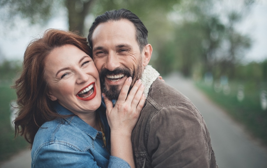 Man and woman with dental implants smiling together