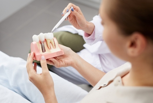 Dentist using model to explain the four step dental implant process