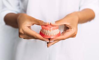 a closeup of a dentist holding dentures