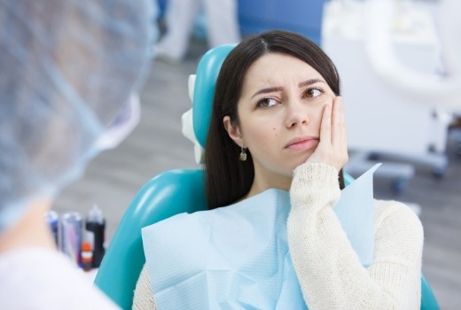 Woman holding cheek before emergency dentistry