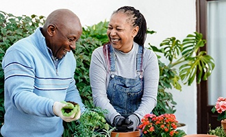 Man and woman smiling while gardening outside