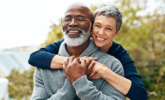 Couple smiling while hugging outside