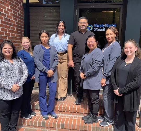 The Simply Dental of Lowell dental team smiling outside of the dental office