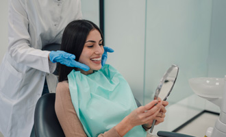 Woman smiling at reflection in handheld mirror