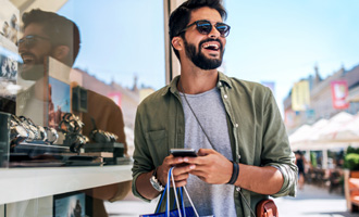 Man with sunglasses smiling while shopping outside