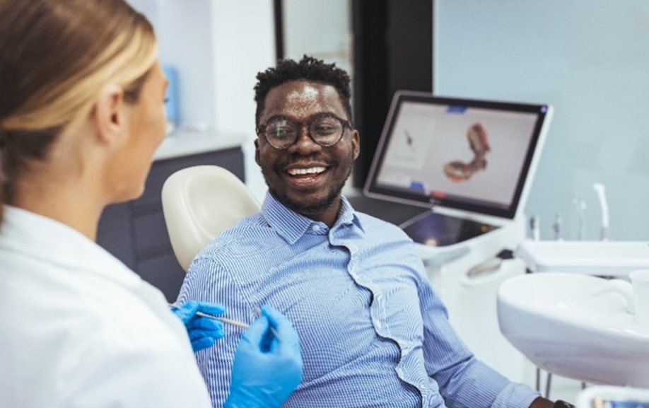 Male patient smiling at dentist while discussing teeth whitening